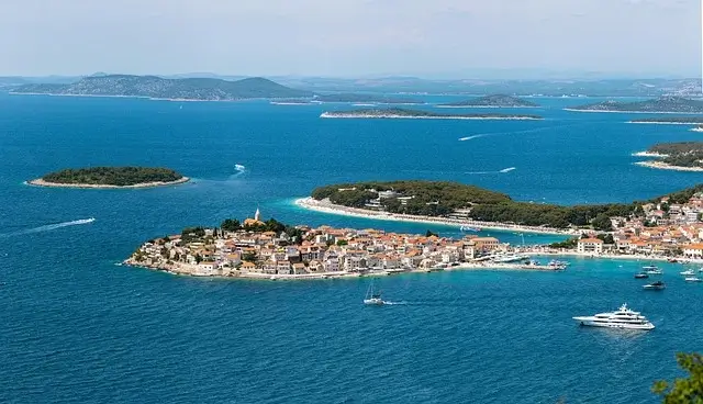 A panoramic view of Hvar Island from a hilltop, showcasing its lush greenery and coastal scenery under a clear sky.