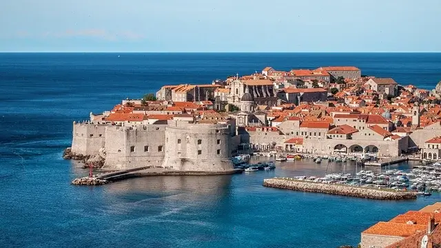 A panoramic view of Dubrovnik's old town, Croatia, showcasing its historic architecture and red-tiled roofs against the Adriatic Sea.