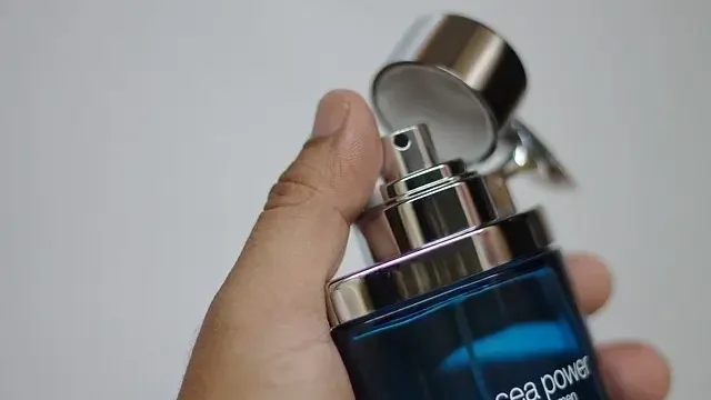A person holding a blue bottle of perfume, showcasing its elegant design and vibrant color