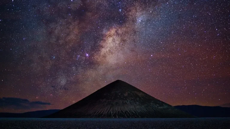 The Milky Way stretches across the night sky above the pyramids in the Atacama Desert, creating a stunning celestial scene.