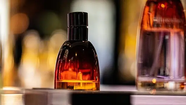 A bottle of perfume elegantly placed on a wooden table, reflecting soft light