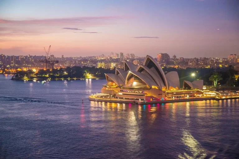 Sydney Opera House illuminated at dusk, showcasing its iconic sail-like architecture against a twilight sky