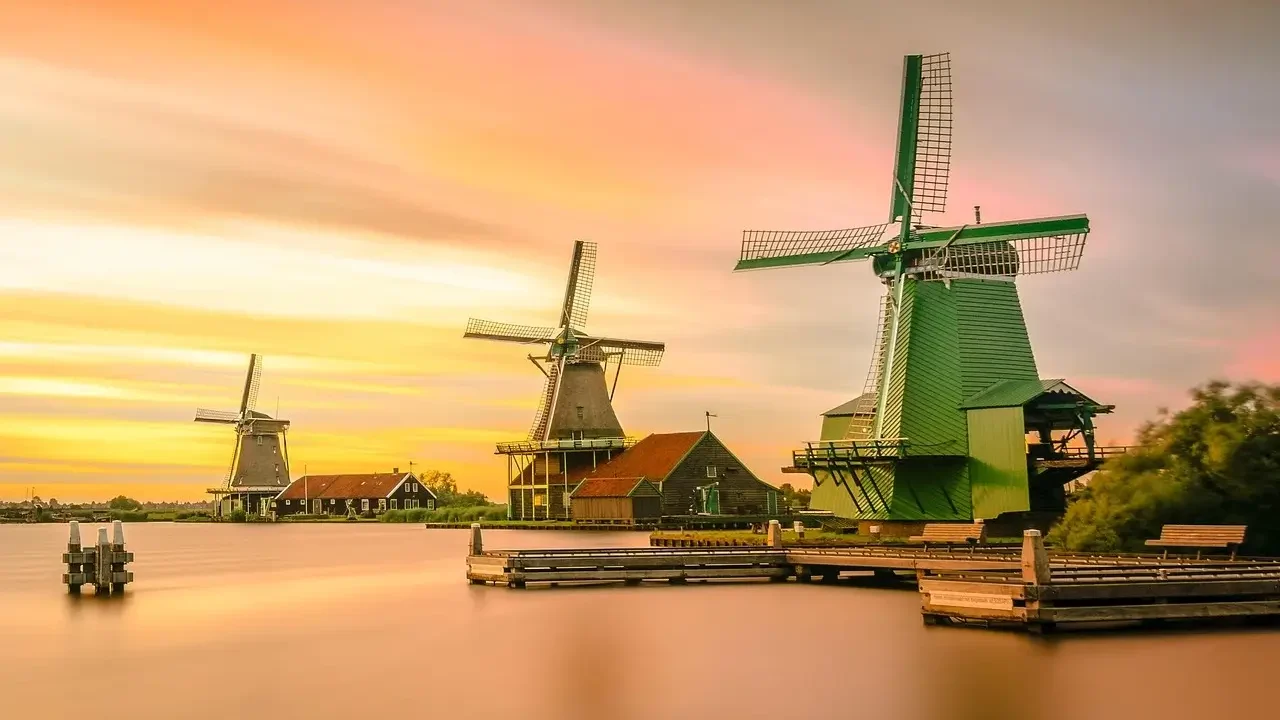 Windmills silhouetted against a vibrant sunset sky in the Netherlands, showcasing a picturesque landscape