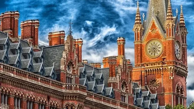 A large building featuring a prominent clock tower with a clock, set against a clear blue sky