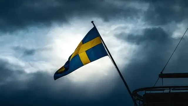 Swedish flag waving on a boat against a dark sky, creating a striking contrast in the night scene