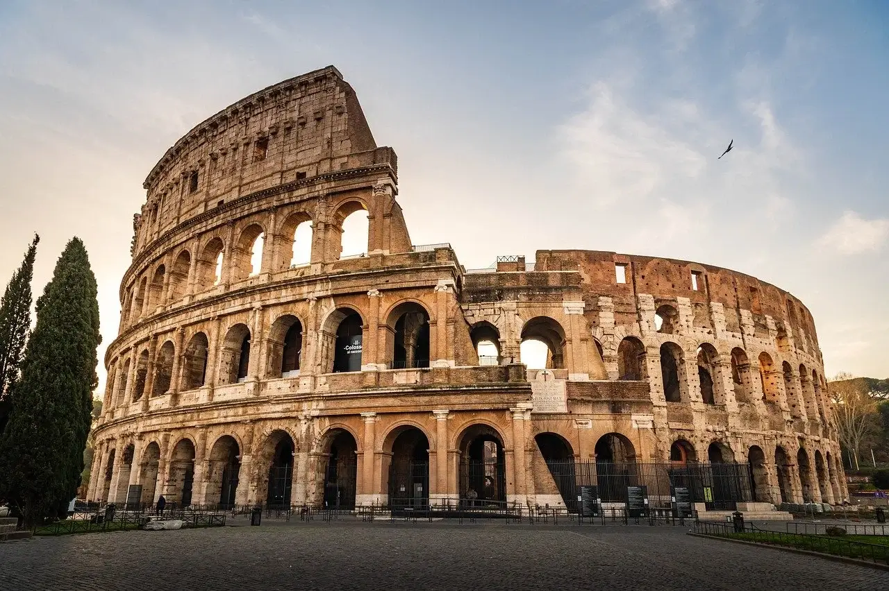 The Colosseum in Rome, Italy, showcasing its iconic arches and ancient architecture against a clear blue sky