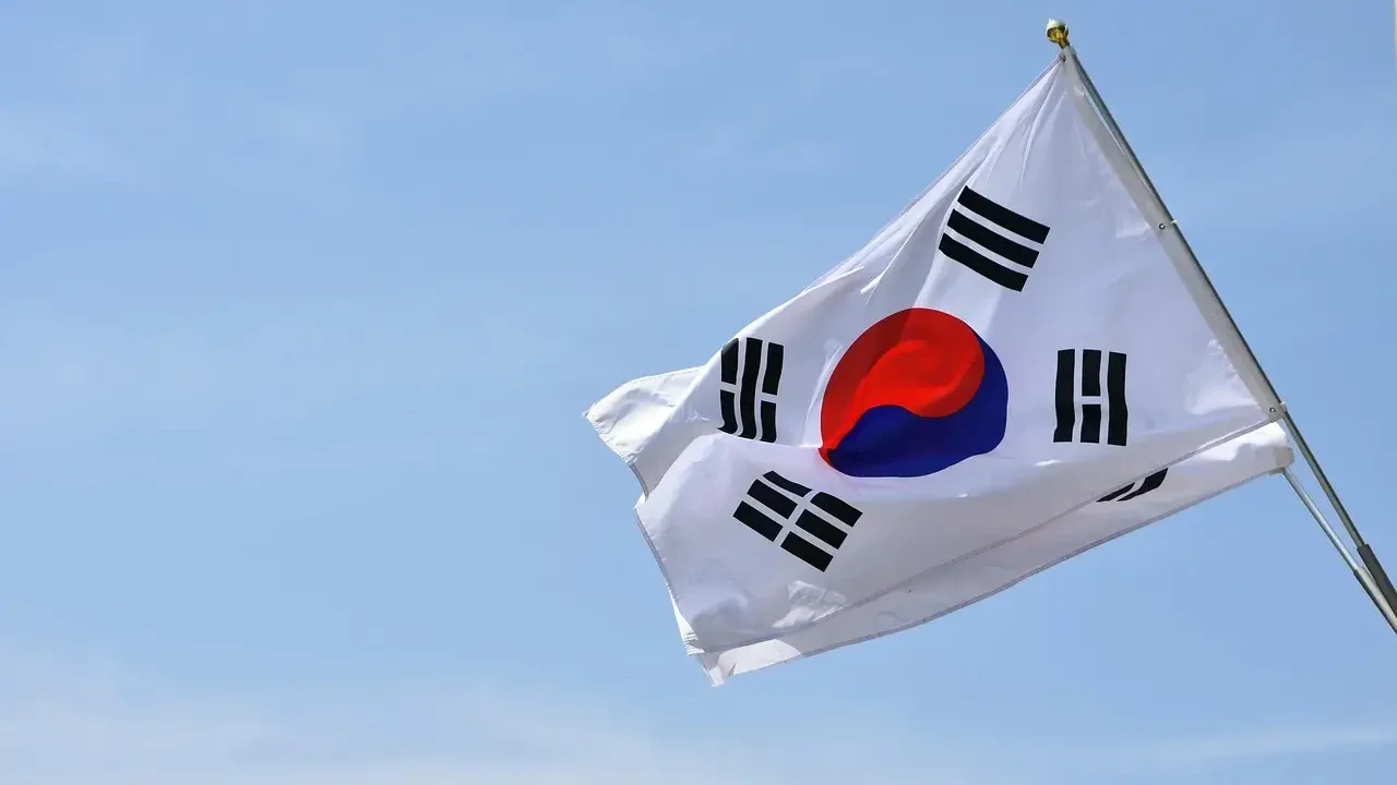 A South Korean flag waving in the wind against a clear blue sky