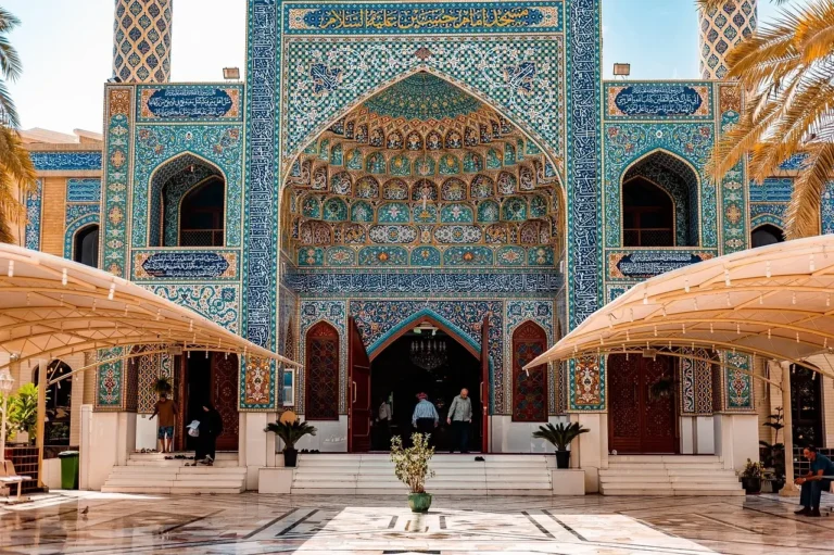The entrance of a mosque adorned with intricate blue and white tilework, showcasing traditional architectural design