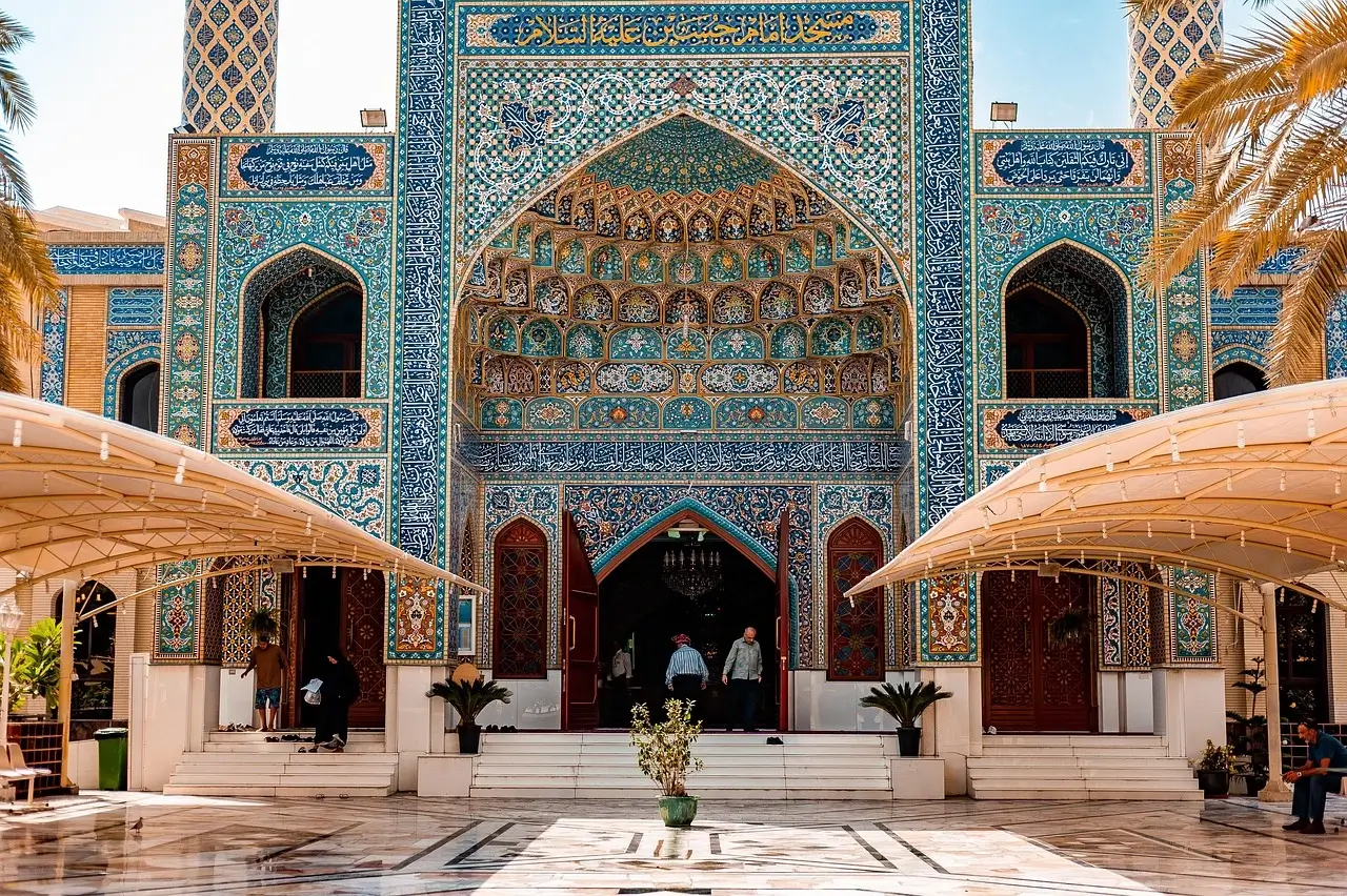 The entrance of a mosque adorned with intricate blue and white tilework, showcasing traditional architectural design