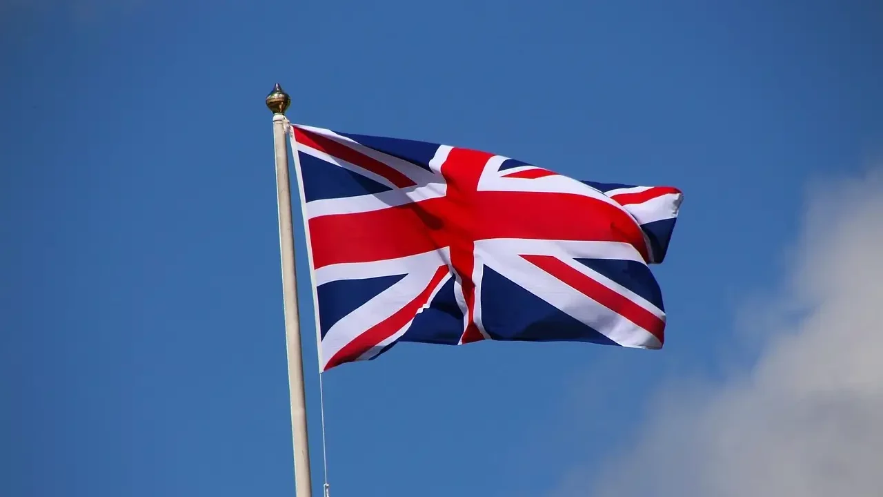 A British flag waving in the wind against a clear blue sky