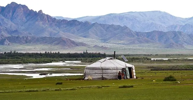  A yurt stands alone in a lush grassy field under a clear blue sky
