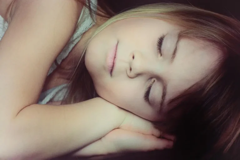 A young girl peacefully sleeping on a bed, surrounded by soft blankets and pillows