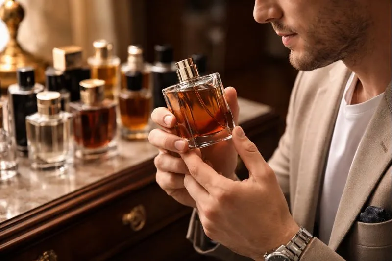 A man holds a bottle of perfume, showcasing its elegant design and label