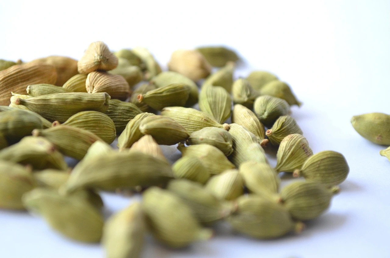 Cardamom seeds scattered on a white background, showcasing their small, oval shape and brownish-green color