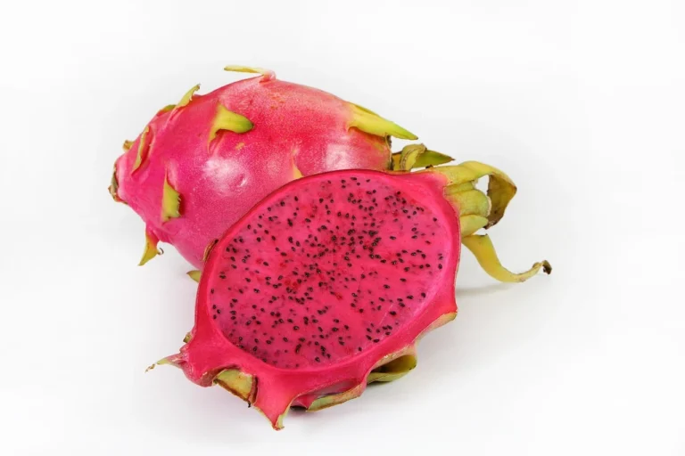 A vibrant dragon fruit cut in half, revealing its white flesh speckled with tiny black seeds