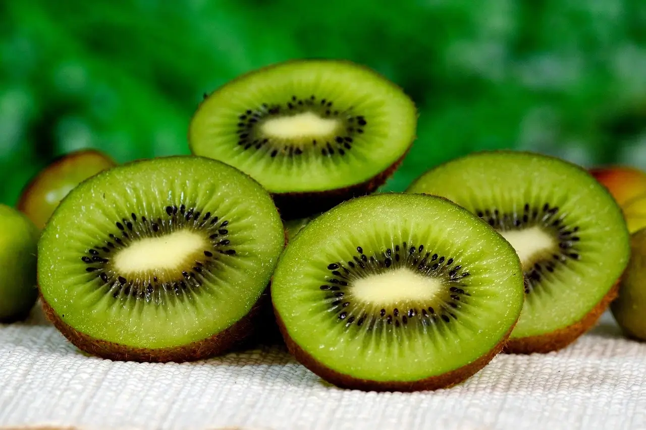 A cluster of ripe kiwis arranged on a wooden table, showcasing their fuzzy brown skin and vibrant green flesh