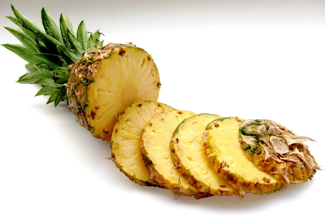A freshly sliced pineapple cut in half, revealing its juicy yellow interior and textured skin