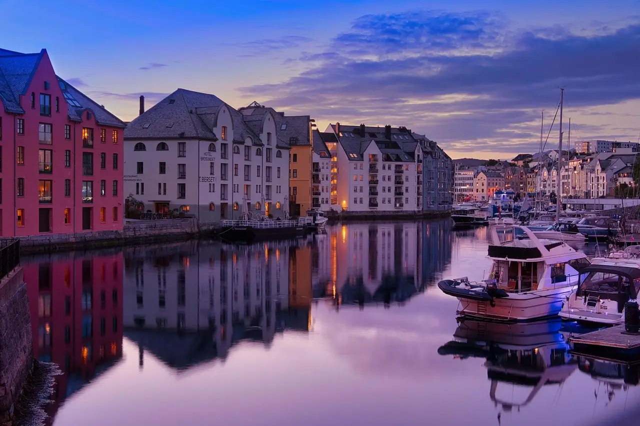 Boats are docked in a tranquil harbor as dusk settles, casting soft shadows on the water's surface