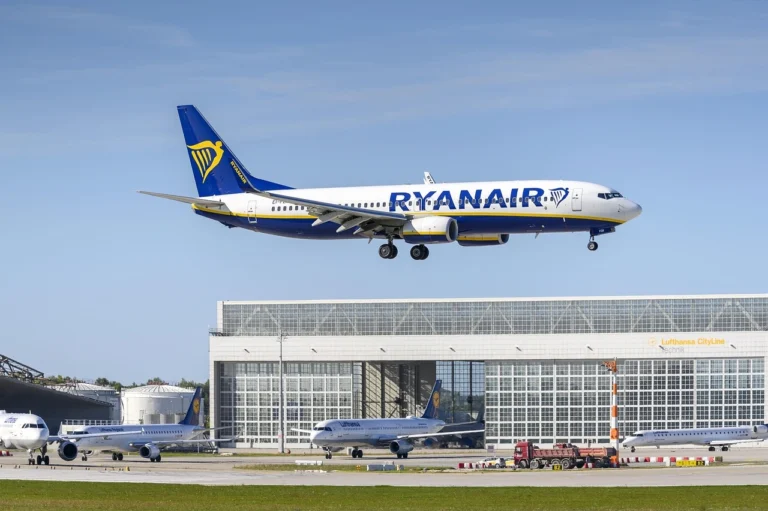 A large airplane ascends into the sky as it takes off from a busy airport runway