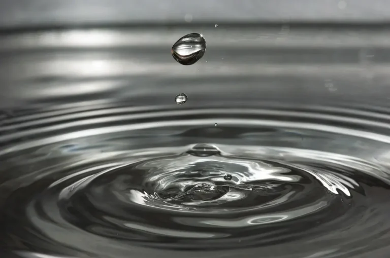 Water droplets splash into a bowl, creating ripples on the surface of the water